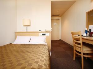 Habitación de hotel con cama, escritorio y mesa. en Hotel LC Gifu Hashima en Hashima