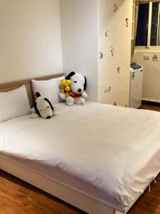 dos animales de peluche sentados encima de una cama en Jacky's House Ximen en Taipéi