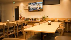 a restaurant with tables and chairs and a tv on the wall at Hotel Sanrriott Osaka Hommachi in Osaka