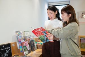 two women looking at a book in a store at Hotel Sanrriott Osaka Hommachi in Osaka