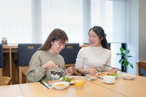 two women sitting at a table eating food at Hotel Sanrriott Osaka Hommachi in Osaka