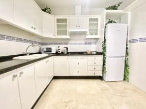 una cucina con armadietti bianchi e frigorifero di Apartamento Andalucía Centro III ad Antequera