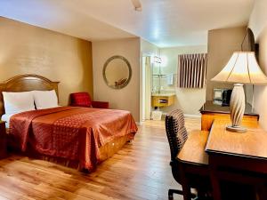 a hotel room with a bed and a desk with a lamp at Franciscan Inn Motel in Vista +18 photos