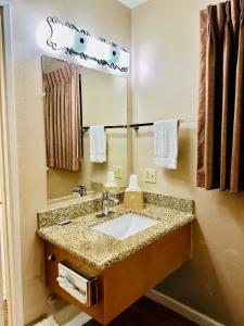 een badkamer met een wastafel en een spiegel bij Franciscan Inn Motel in Vista