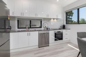 a kitchen with white cabinets and stainless steel appliances at Chic 2-Bed Home with Backyard, BBQ & Parking in Phillip