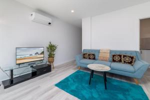uma sala de estar com um sofá azul e uma televisão em Chic 2-Bed Home with Backyard, BBQ & Parking em Phillip