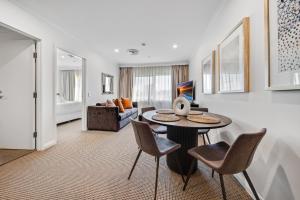 a living room with a table and chairs and a couch at Center 1-Bed with Sauna, Gym, BBQ & Parking in Canberra