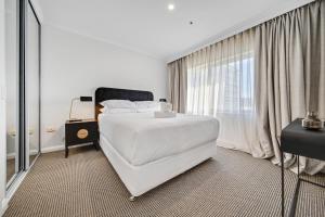 a white bedroom with a bed and a window at Center 1-Bed with Sauna, Gym, BBQ & Parking in Canberra