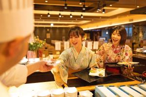 a couple of women sitting at a counter eating food at Ooedo Onsen Monogatari Awara in Awara
