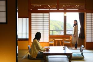 a woman sitting at a table in a room at Ooedo Onsen Monogatari Awara in Awara