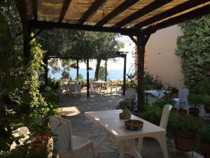 un patio con mesa y sillas bajo una pérgola de madera en Kostas House, en Gerakini