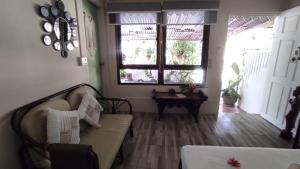 Baan sikhao Yanui في شاطئ راوايْ: غرفة معيشة مع أريكة ونوافذ