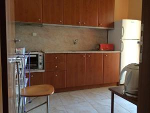 cocina con armarios de madera y nevera blanca en Kostas House, en Gerakini