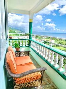a balcony with an orange chair and a view of the ocean at Tropical Penthouse Overlooking Caribbean Sea in Mahaut