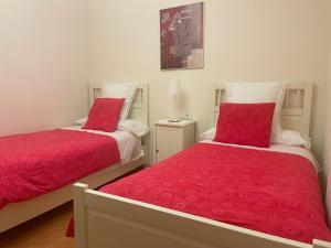 two beds with red covers in a bedroom at Apartamento Costa con Parking Privado Incluido in Zumaia