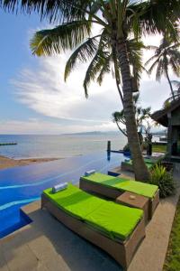 a swimming pool with a palm tree next to the ocean at Bayside Bungalows in Candidasa