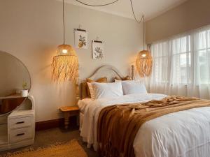 a bedroom with a large bed and two lights at Revell St Beach Bungalow in Hokitika