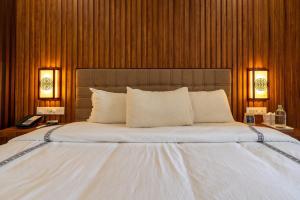 a bedroom with a large white bed with two lamps at Mansha Palace in Port Blair