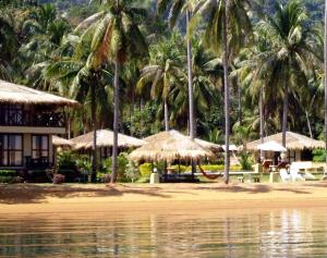 a beach with umbrellas and chairs and palm trees at Amber Sands Beach Resort in Ko Chang