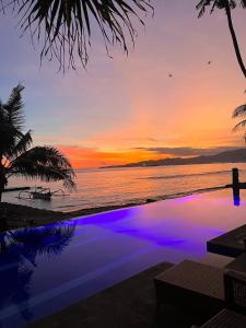 a sunset over the ocean with a swimming pool at Bayshore Villa in Candidasa