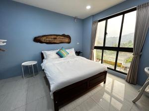 Dormitorio azul con cama y ventana grande en Forgather B&B, en San-min