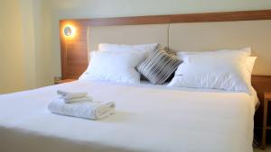 a bedroom with a white bed with towels on it at Enn Business Hotel in Kampala