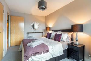 1 dormitorio con 1 cama grande con almohadas moradas en ExCel, O2, Canary Wharf, London City Airport - Free Parking, en Londres