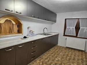 a kitchen with gray cabinets and a sink and a window at Pensiunea Ana Maria Durau in Durau