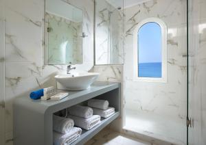 a white bathroom with a sink and a mirror at Coral Hotel in Ierápetra