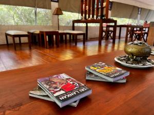 dwa magazyny i wazon na drewnianym stole w obiekcie Yala Hotel Lion 