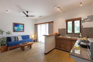 a kitchen and living room with a blue couch at L'Hirondelle Self Catering Guest House in Anse Possession