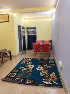 a room with two red chairs and a blue rug at Behala home stay in Kolkata