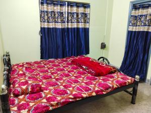 a bed with a red comforter and purple flowers at Behala home stay in Kolkata