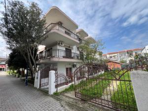 a white house with a fence in front of it at PELEKAN rooms and apartments athina 11 in Pefkohori