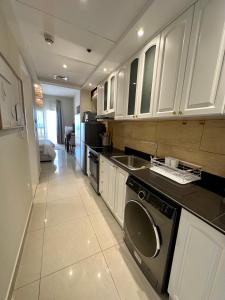 a kitchen with white cabinets and a washer and sink at Mediterranean breeze in Ras al Khaimah