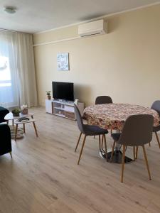uma sala de estar com uma mesa e cadeiras e uma televisão em City Apartment em Piešťany