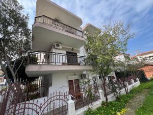 a white house with a balcony and a fence at PELEKAN rooms and apartments athina 11 in Pefkohori