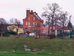 a large red brick building in a grassy field at Gästewohnung Heinrich Heine Schule in Bad Dürrenberg