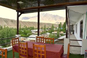 a table and chairs on a balcony with a view of mountains at Hotel Rangyul in Kargil