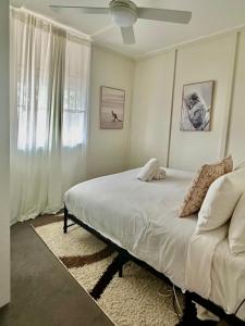 Habitación blanca con cama y ventana en Katoomba Hideaway - Blue Mountains Modern Getaway, en Katoomba
