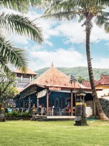 a restaurant with a palm tree and a building at Bayshore Residence in Candidasa