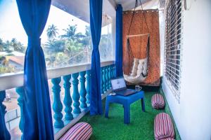 a balcony with a laptop on a table and a hammock at Beyond the Reef - NestinGoa Homestays in Arambol