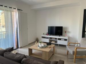 a living room with a couch and a tv at Techas Near Beach Apt with Pool in Praia
