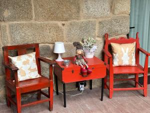 a red table with a doll sitting on it next to two chairs at A XANELA 