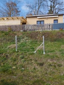 einen Zaun im Gras vor einem Haus in der Unterkunft Müller's Ferienbungalow "Zur Göltzschtalbrücke" in Greiz