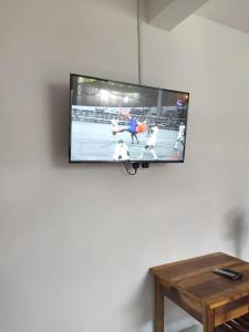 TV de pantalla plana colgada en una pared junto a una mesa en Kai Kazee Ella, en Ella