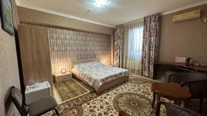 um quarto com uma cama, uma secretária e uma cadeira em Cannes Hotel em Shymkent