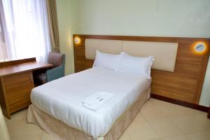 a bedroom with a white bed with a wooden headboard at Enn Business Hotel in Kampala