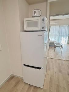 a white refrigerator with a microwave on top of it at Neighbor's Hotel 広島駅北口 in Hiroshima