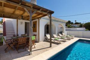 eine Terrasse mit Tisch und Stühlen neben einem Swimmingpool in der Unterkunft Villa Serena by Mauter Villas in Cala en Porter